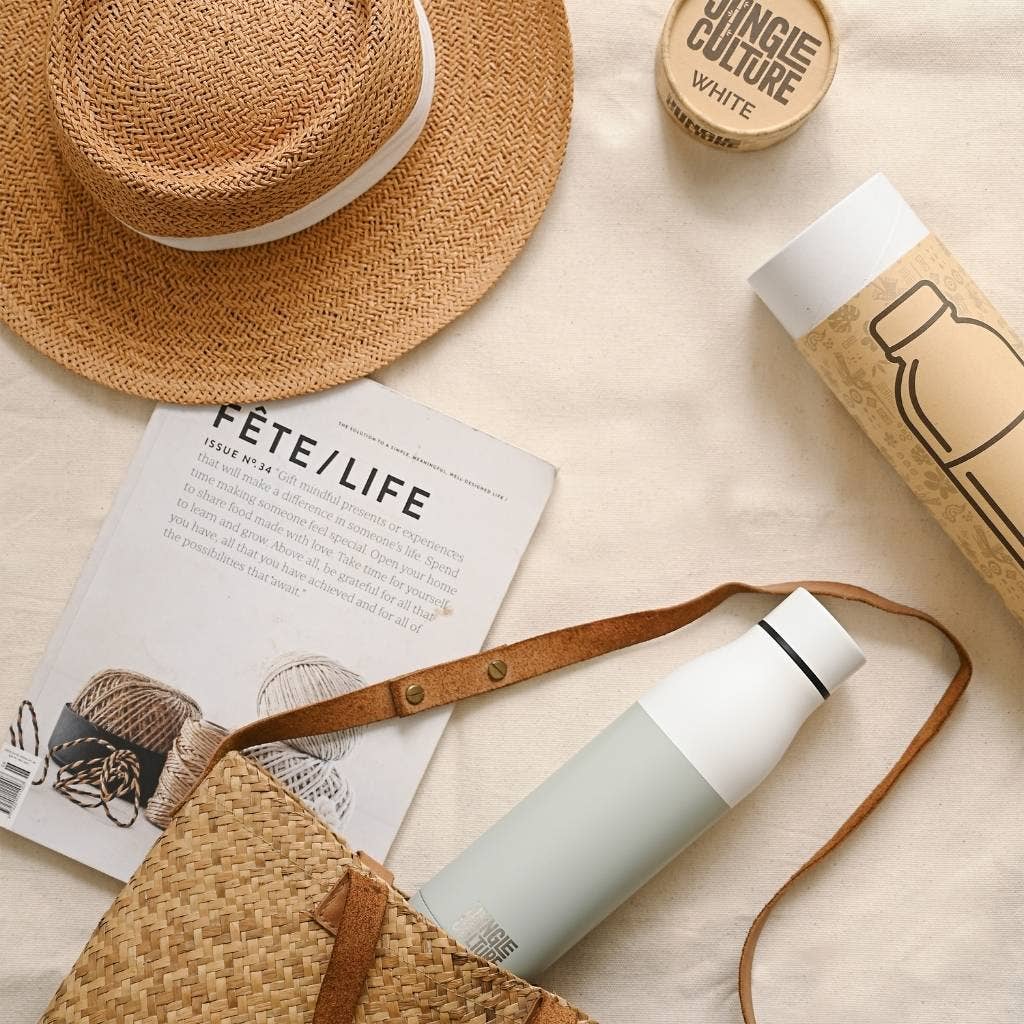 Insulated stainless steel water bottle flat lay with display box and lifestyle props
