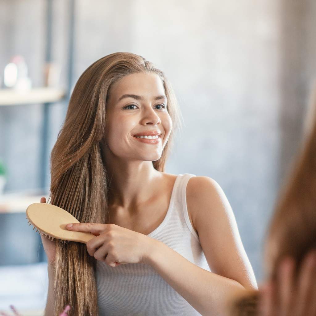woman holding bamboo brush over dry hair for detangling