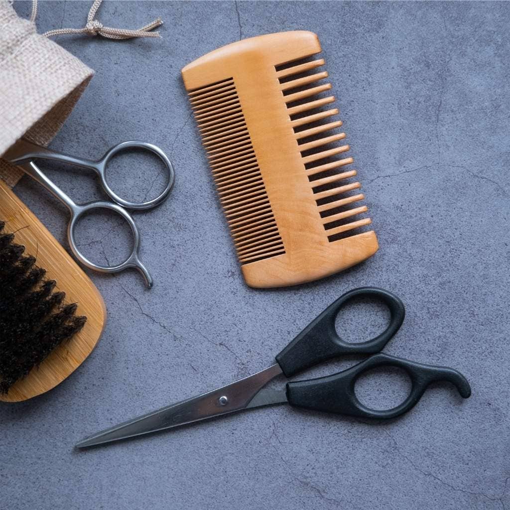 Close-up of fine teeth on beard comb with smooth wood grain finish with other shaving items