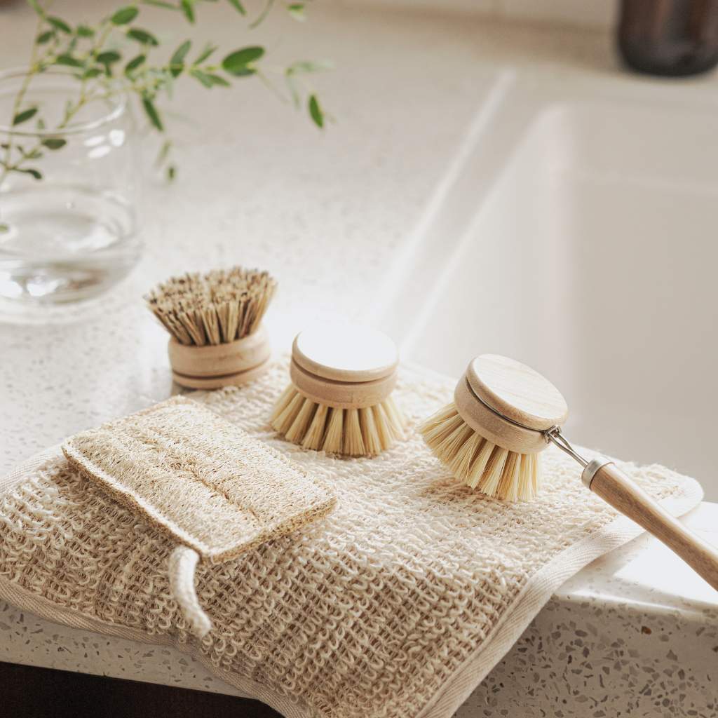 Bamboo kitchen brush set with long handle, refill heads and loofah on ceramic sink draining board