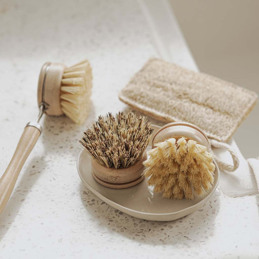 Bamboo kitchen brush set with long handle, refill heads and loofah on ceramic sink close up