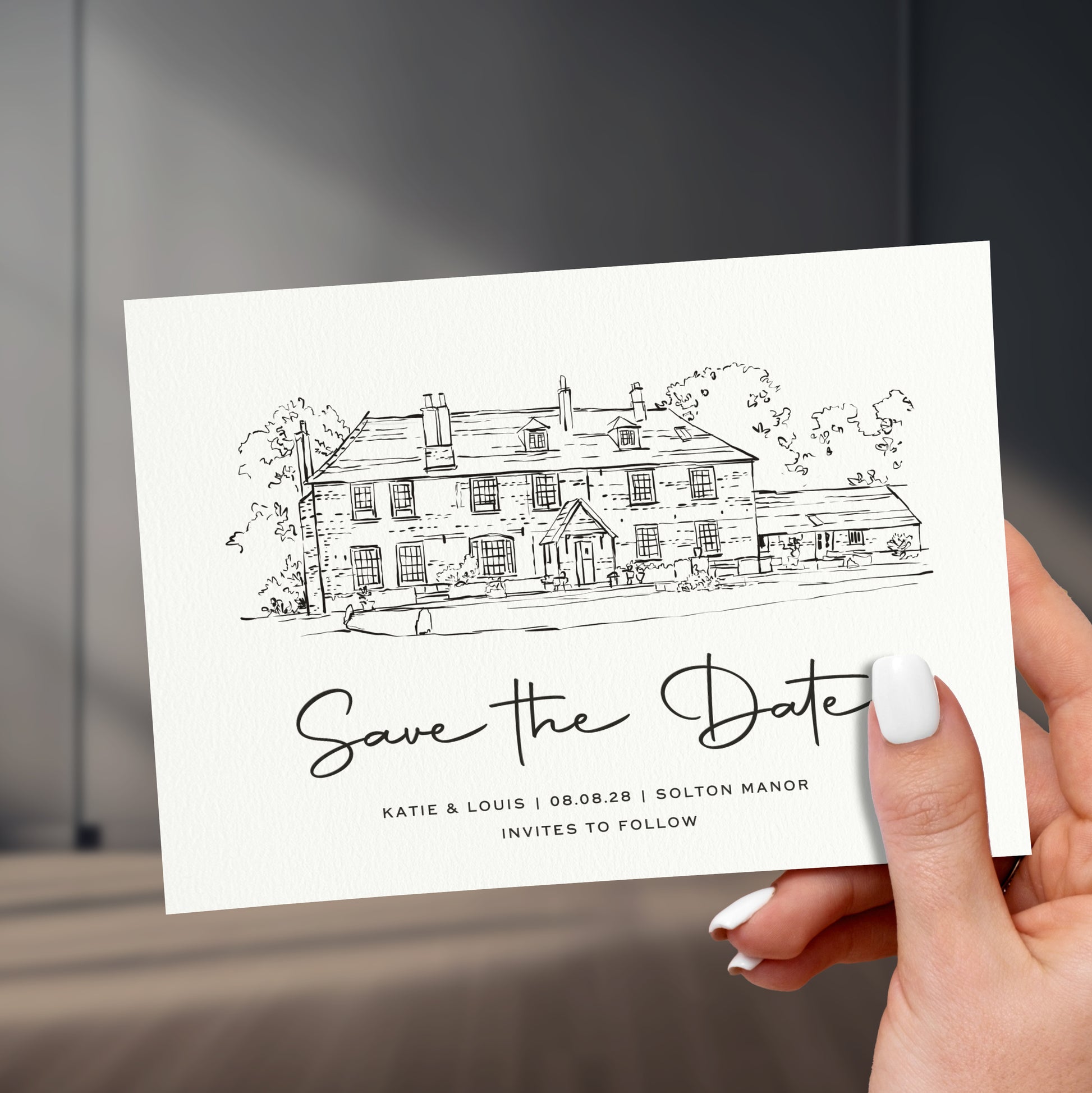 black and white venue sketch save the date card held in a hand with painted white names, held up against a stylish sleek room background