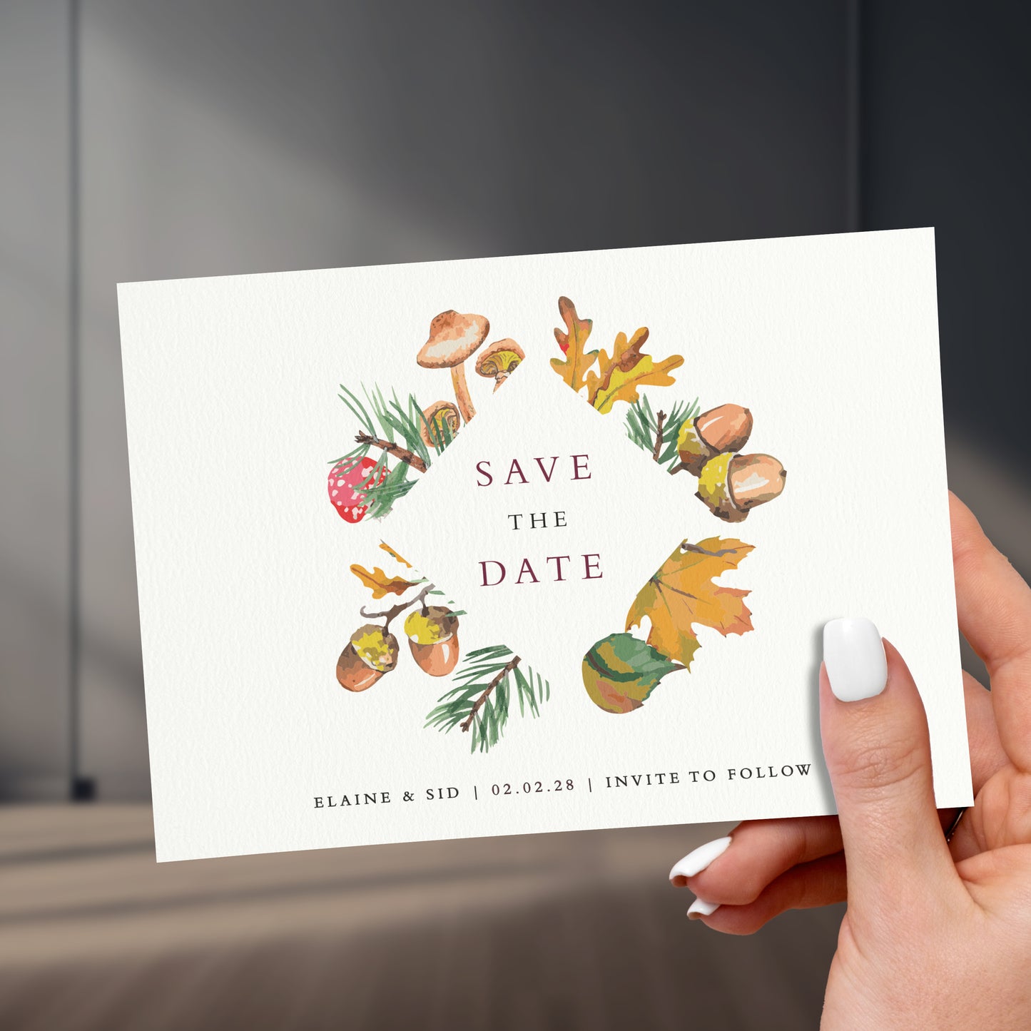 brown orange mushroom woodland save the date card held in a hand with painted white names, held up against a stylish sleek room background