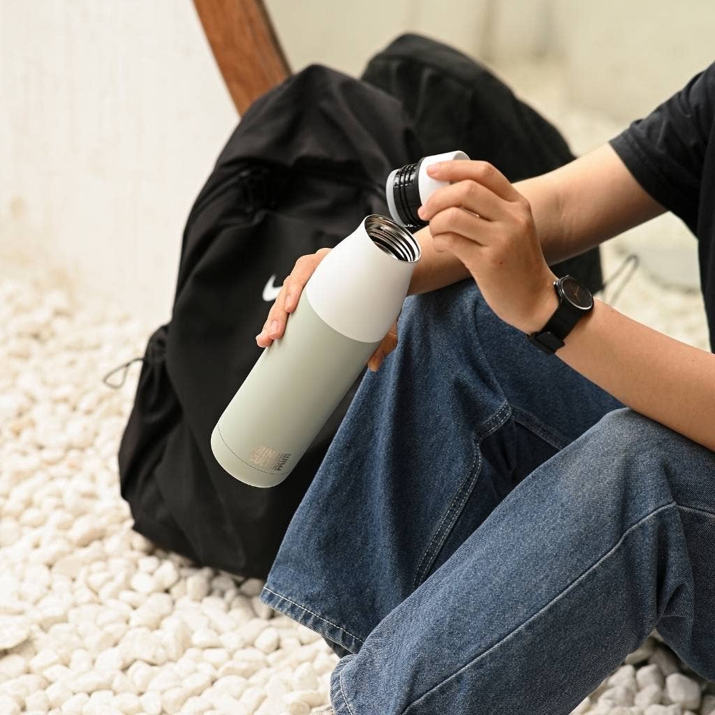 Insulated stainless steel water bottle being drank from after gym workout.