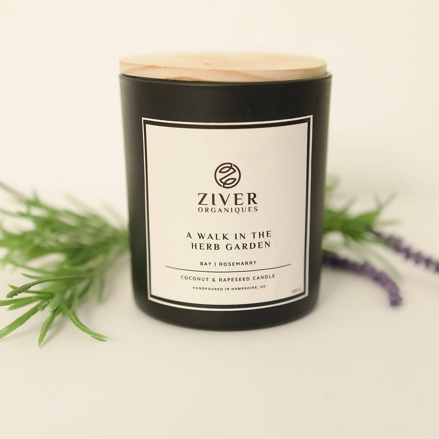 Herbal garden scented candle in glass jar on wooden table with lavender
