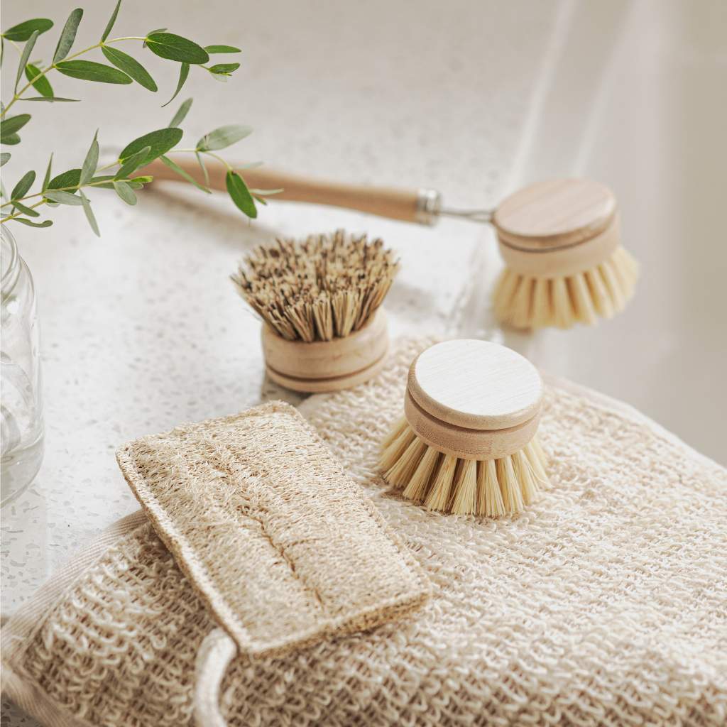 Bamboo kitchen brush set with long handle, refill heads and loofah on ceramic sink close up