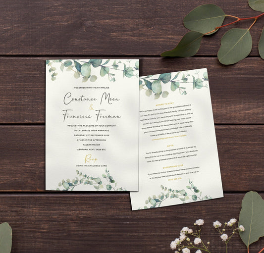 Flat lay of a botanical wedding invitation for Constance Moon and Francisce Freeman, wrapped in a trailing eucalyptus garland. Displayed on a dark wood table with fresh eucalyptus and baby’s breath, reverse card includes guest info in soft green text.