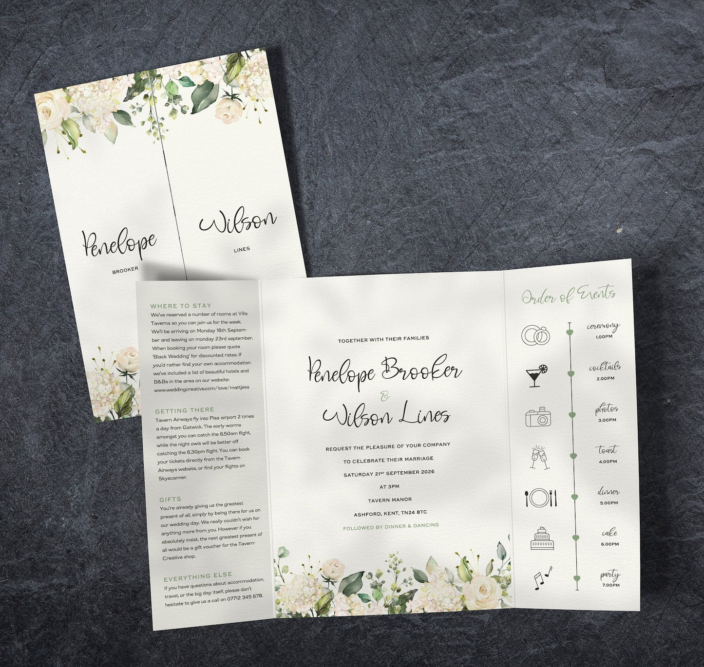 White and green floral gatefold wedding invitation, showing a timeline panel, guest information and the main information. The invitation is set on a table next to props.