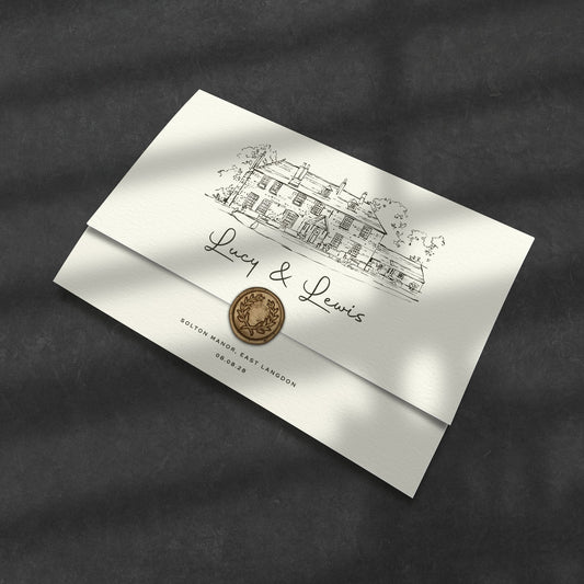 black and white venue sketch wedding invitations in the wallet fold format with a gold wax seal, set on a dark grey table