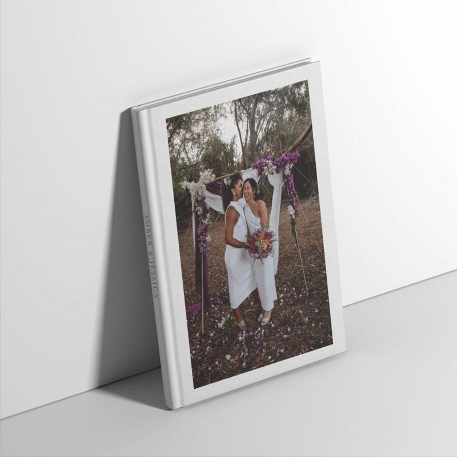 Hardcover personalised wedding photo album propped up against a white wall