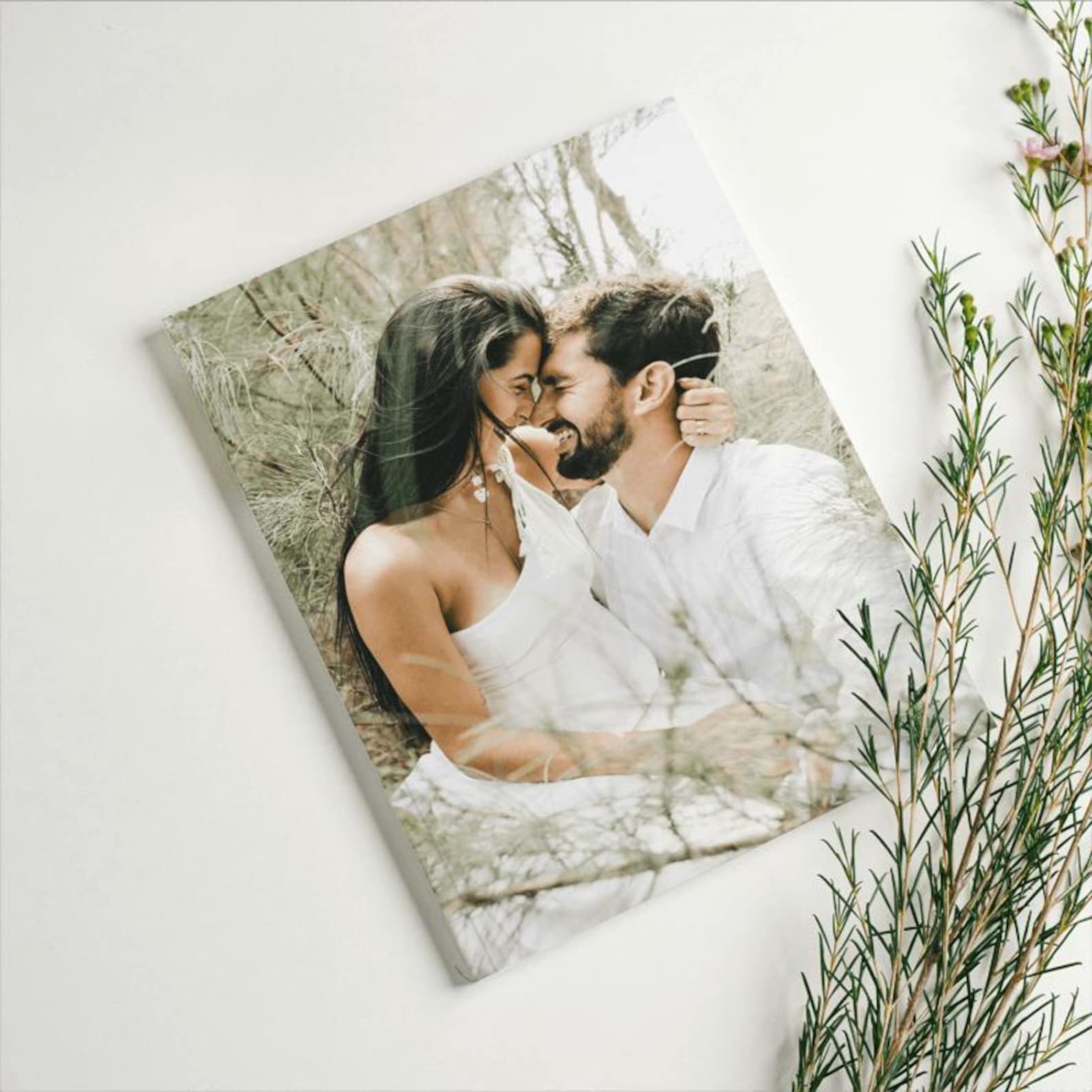 Hardcover personalised wedding photo album closed on coffee table with couple's photos displayed