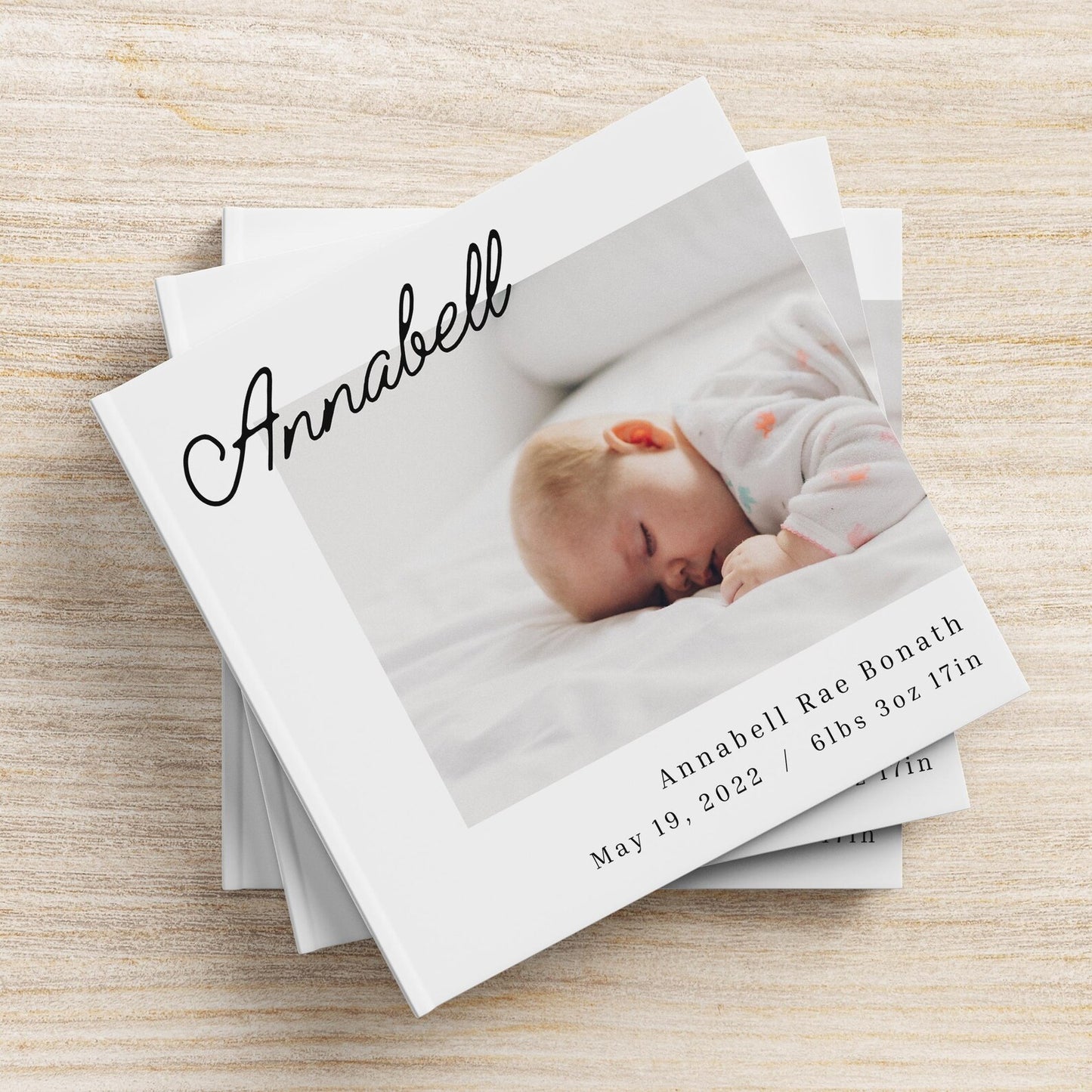 Hardcover personalised baby photo album open on coffee table with baby photos displayed