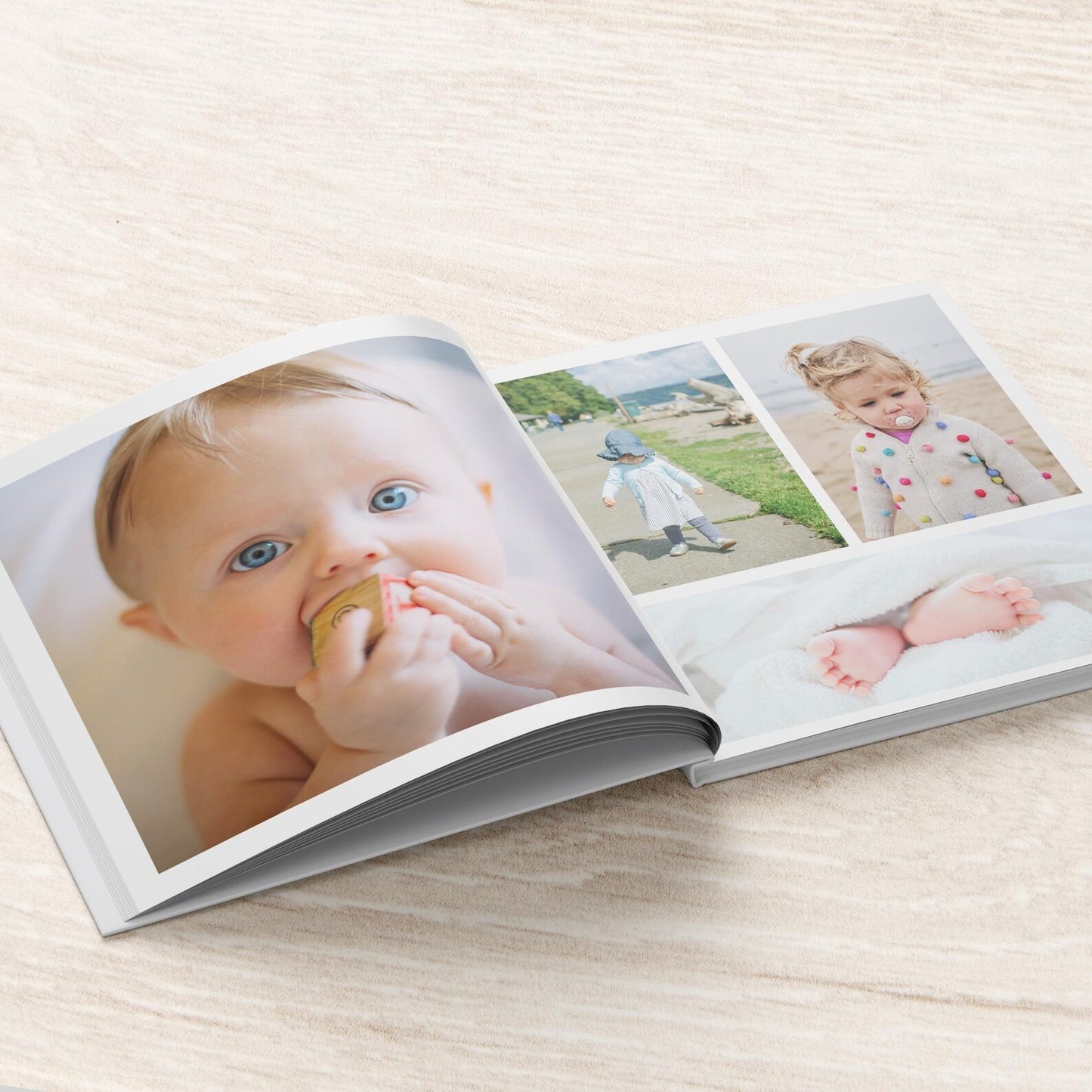 Hardcover personalised baby photo album open on coffee table with baby photos displayed