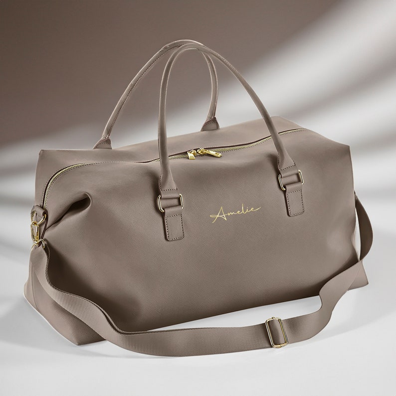 Faux leather travel holdall styled on bed with accessories