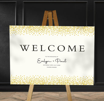 gold confetti A1 welcome sign board on a brown easel in a wedding venue room with stylish decor