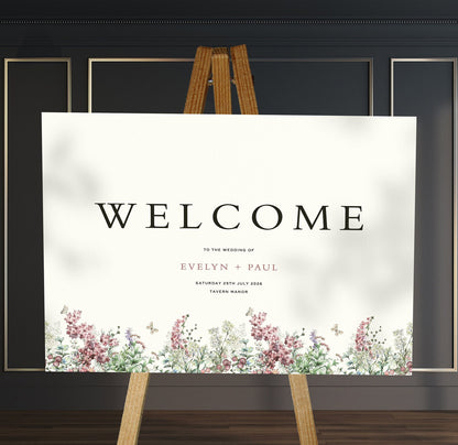 purple and sage wildflowers A1 welcome sign board on a brown easel in a wedding venue room with stylish decor