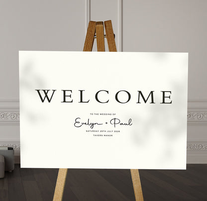black and white minimalist A1 welcome sign board on a brown easel in a wedding venue room with stylish decor