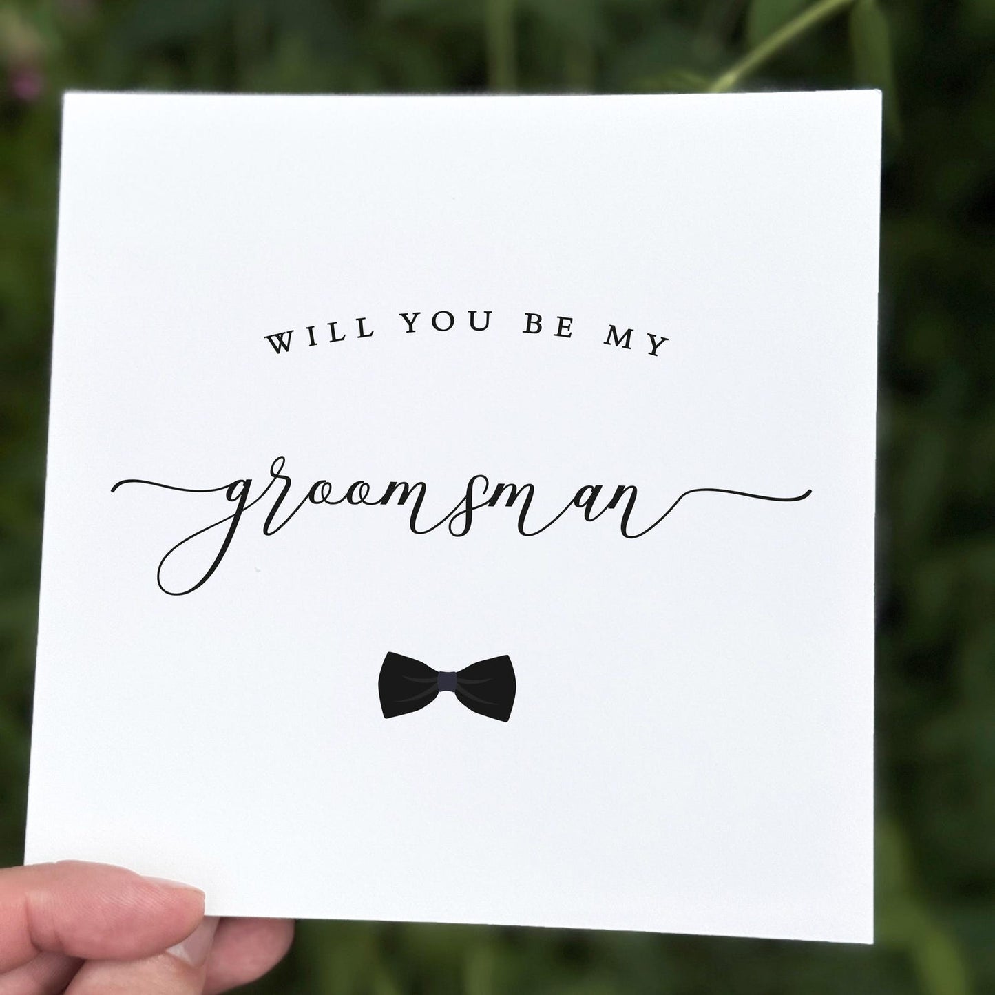 Monochrome groomsman proposal card featuring stylish text and a black bow tie graphic.