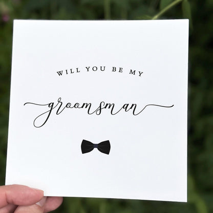 Monochrome groomsman proposal card featuring stylish text and a black bow tie graphic.