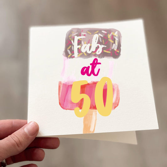 Fab at 50 birthday card featuring illustrated ice lolly design with pink, brown and yellow sprinkles, held in hand against neutral background
