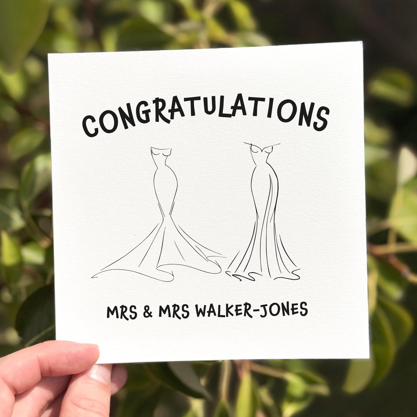 Wedding congratulations card featuring two outlined wedding dresses and the word ‘Congratulations’.