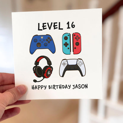 Gamer-themed birthday card showing four colourful controllers and headset, text reads ‘Level Up Happy Birthday’.