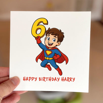 Kids birthday card with a cartoon superhero flying while holding a yellow number six, printed on textured card.