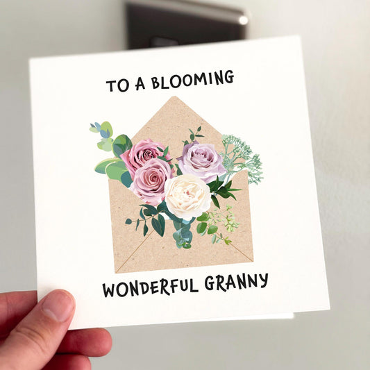 Elegant floral card with pastel roses and greenery arranged in a kraft envelope, captioned ‘To a blooming wonderful granny’.
