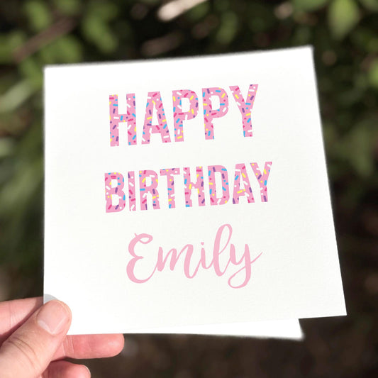 White square card with bold pink confetti letters reading ‘Happy Birthday’ and space for personalised name.