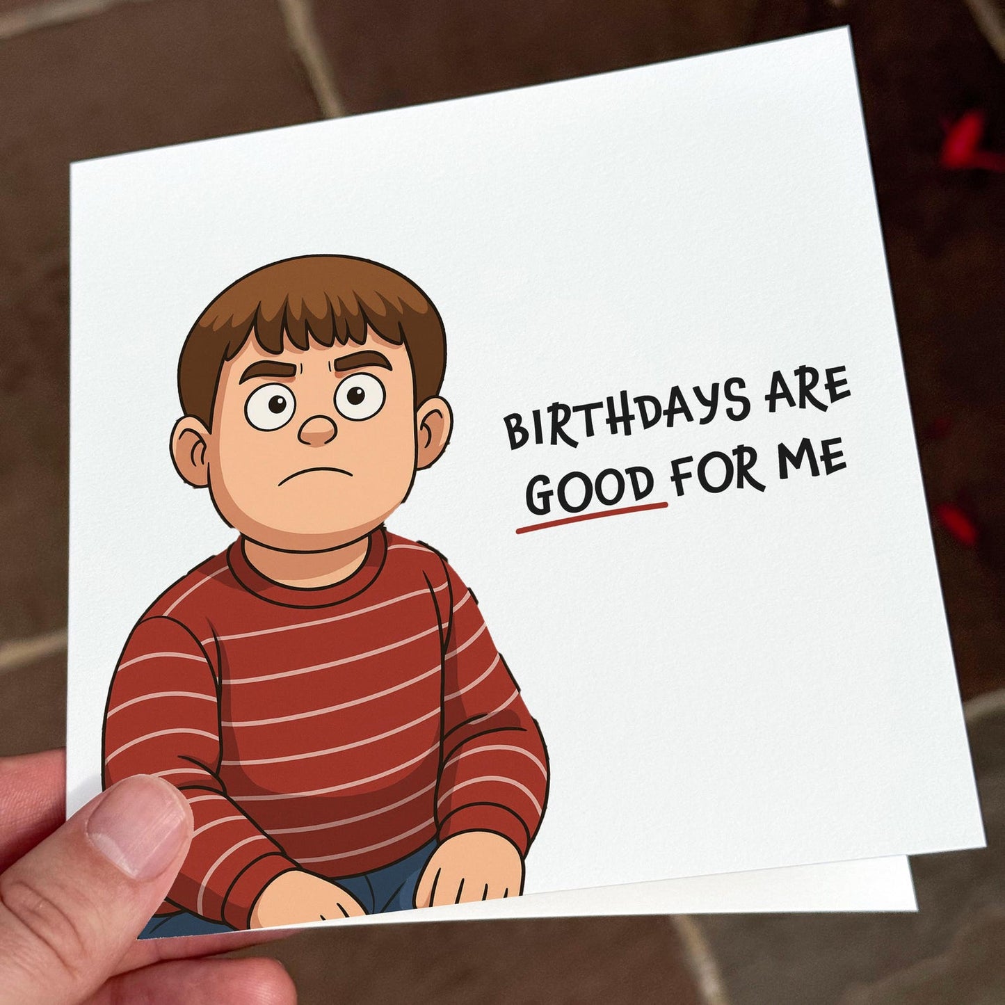 Funny cartoon birthday card showing a grumpy boy in a red striped jumper with the text ‘Birthdays are good for me’.