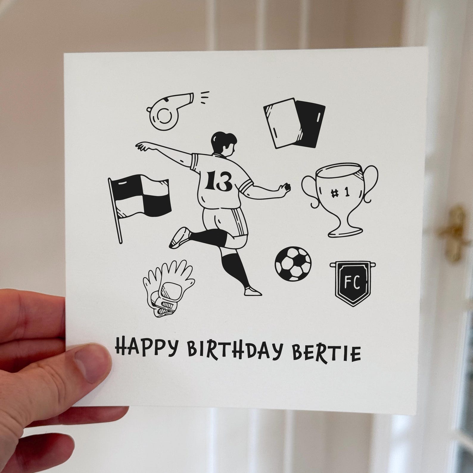 Birthday card showing a football player kicking a ball surrounded by trophies and football symbols, printed on white card.