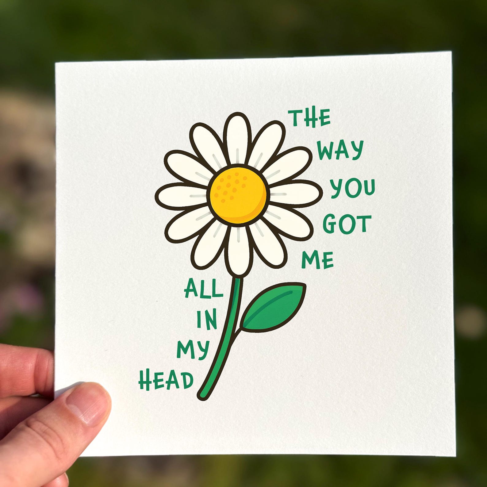 Love card featuring a white daisy with green text reading ‘The Way You Got Me All In My Head’.