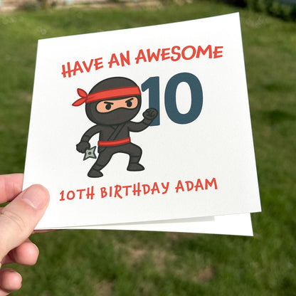 Birthday card featuring a cartoon ninja with red headband and large blue number ten, printed on textured white card.