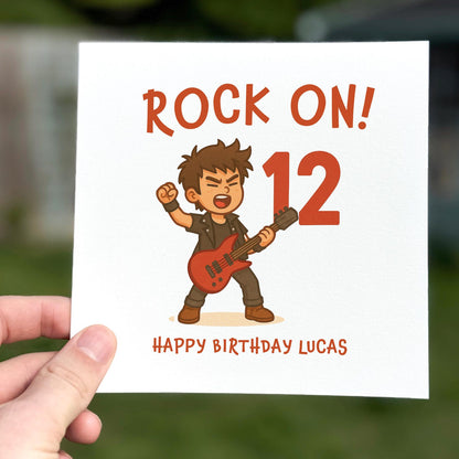 Birthday card featuring a cartoon rock guitarist holding a red guitar with the words ‘Rock On!’ and a large red number.