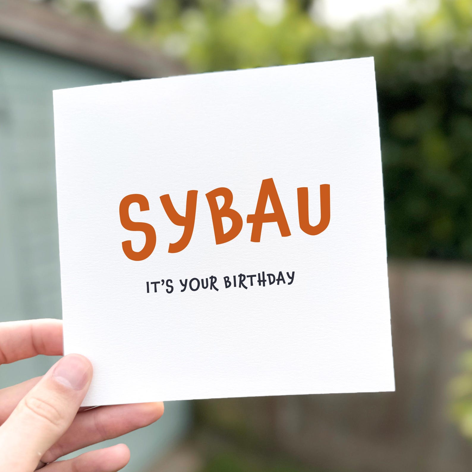 Funny birthday card with bold orange text reading ‘SYBAU – It’s your birthday’.