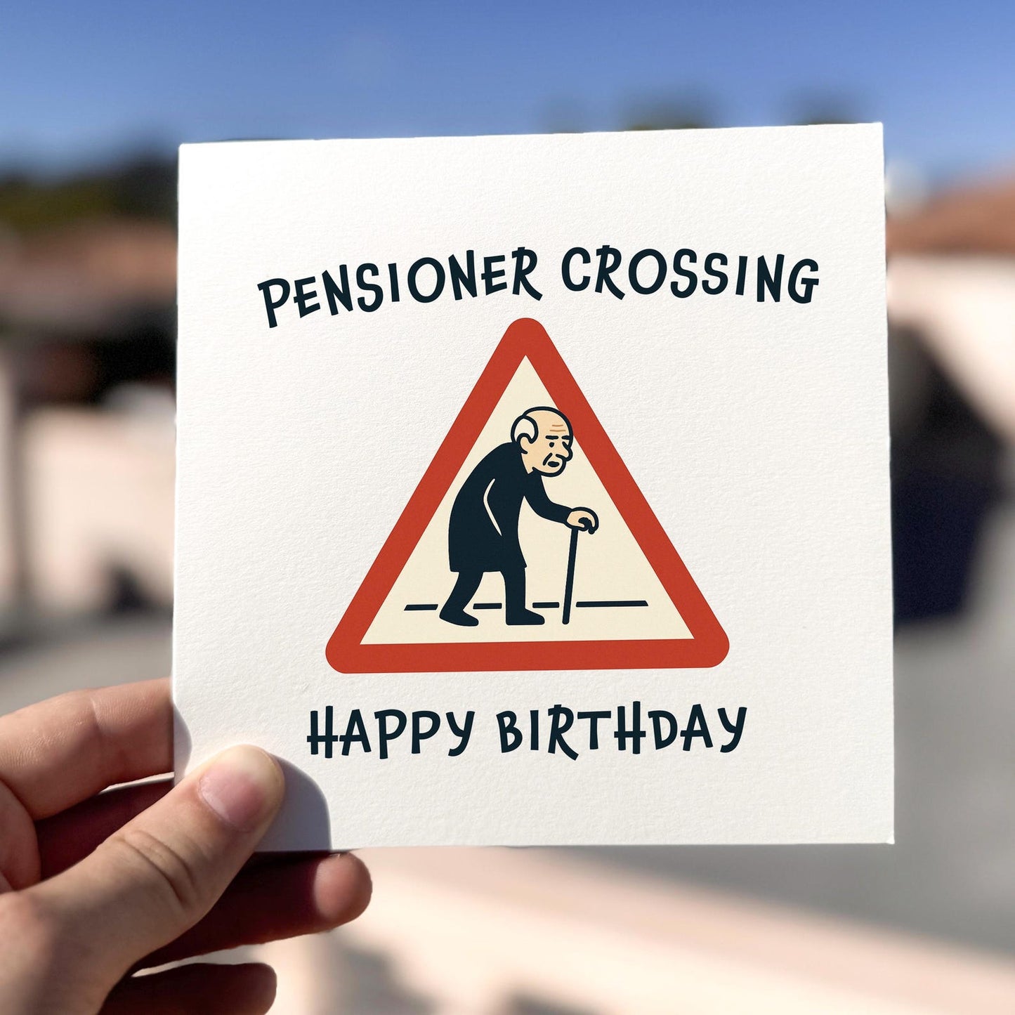 Pensioner Crossing Birthday Card card being held outdoors, showing front design clearly.