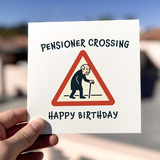 Pensioner Crossing Birthday Card card being held outdoors, showing front design clearly.