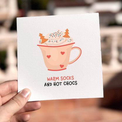 Cosy festive card featuring a mug of hot chocolate with the text ‘Warm Socks And Hot Chocs’.