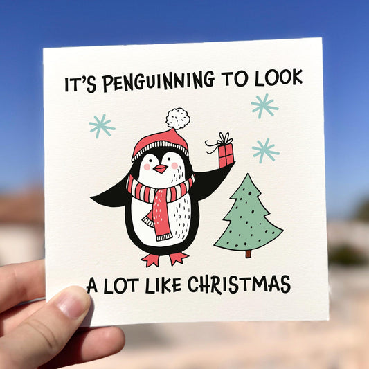 Funny penguin Christmas card with the phrase ‘It’s Penguinning To Look A Lot Like Christmas’.