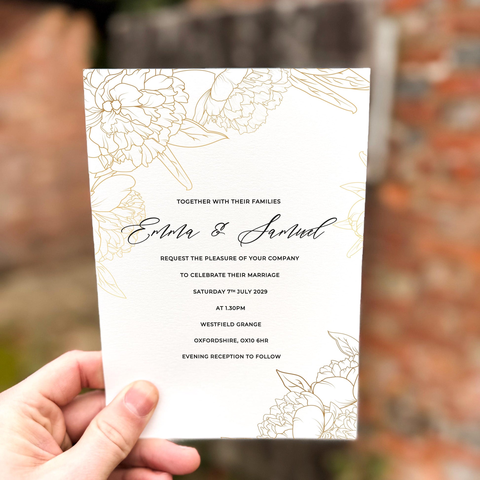 Hand holding a wedding invitation featuring delicate gold line-art florals with a minimalist layout and modern script names.