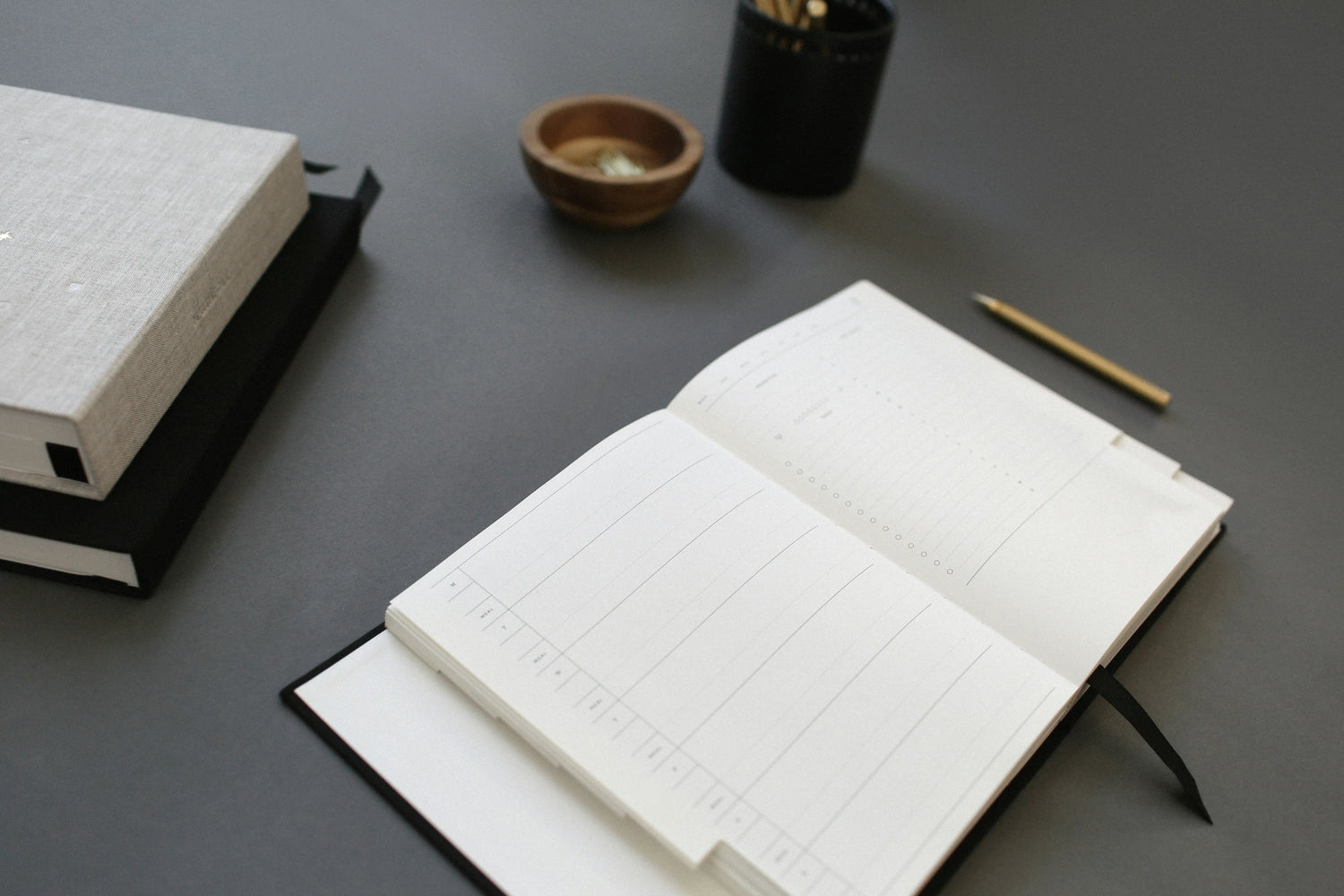 Open notebook on a gray surface with a pen and small bowl nearby